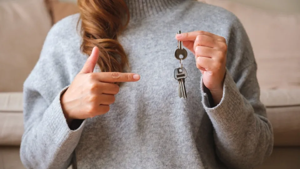 Mulher a segurar um molho de chaves de casa e a apontar para ele.