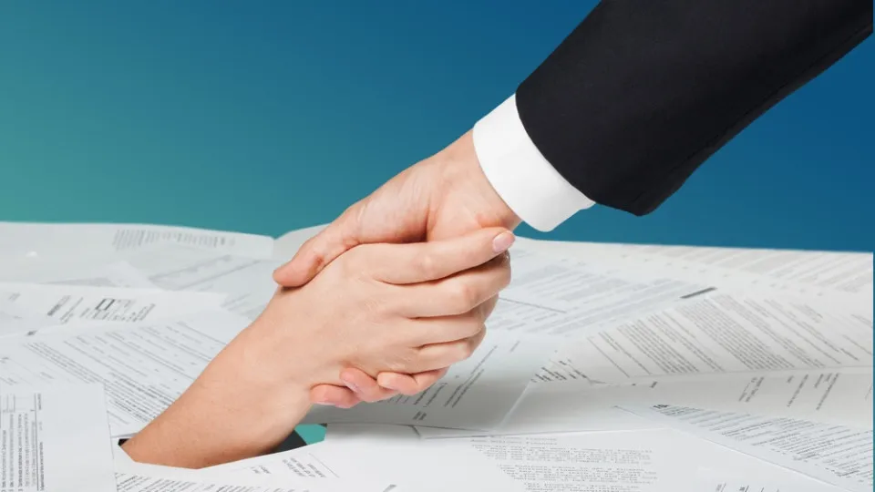 Aperto de mão sobre documentos, representando um acordo associado a um crédito habitação