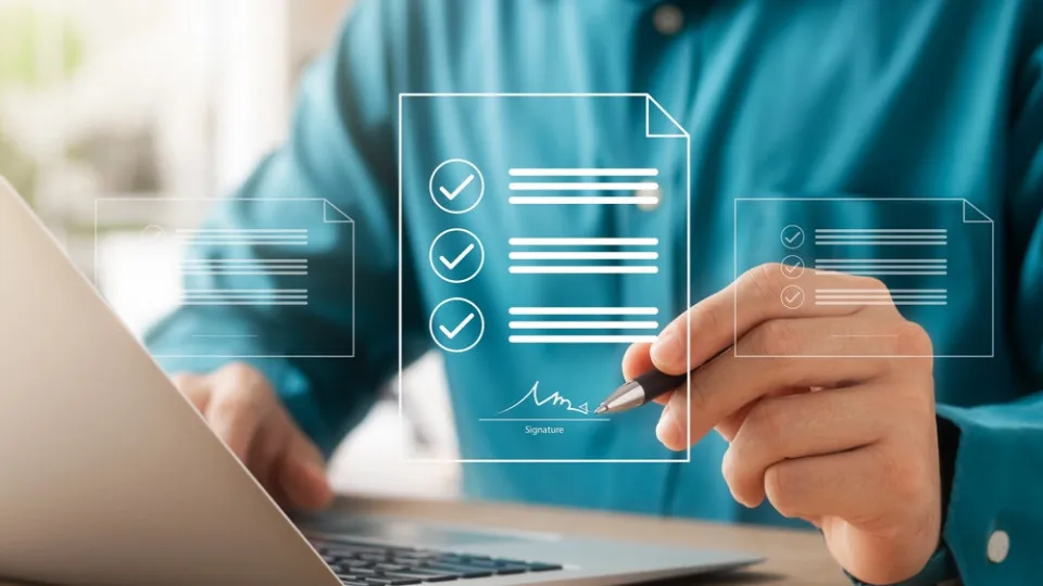 Pessoa a utilizar o portátil enquanto analisa documentos digitais, simbolizando o apoio de um intermediário de crédito na compra de casa.