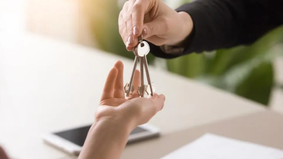 Entrega das chaves de uma casa, simbolizando o primeiro passo na compra de um imóvel