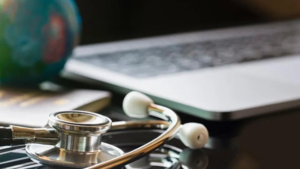 Estetoscópio junto a um computador portátil, simbolizando a contratação de seguros online
