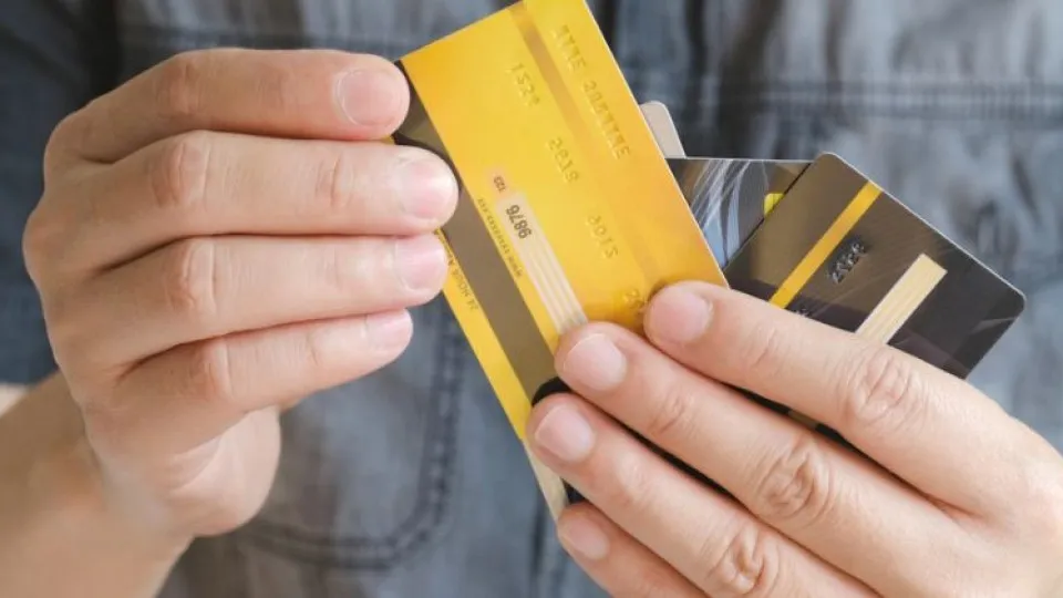 Pessoa a segurar vários cartões de crédito, representando a gestão de múltiplos créditos familiares