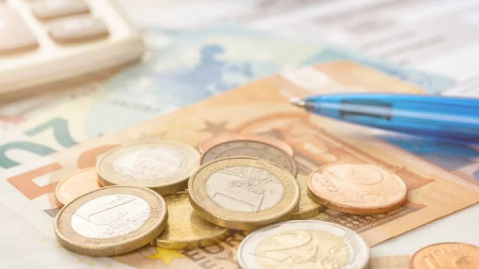 Moedas e caneta azul por cima de notas