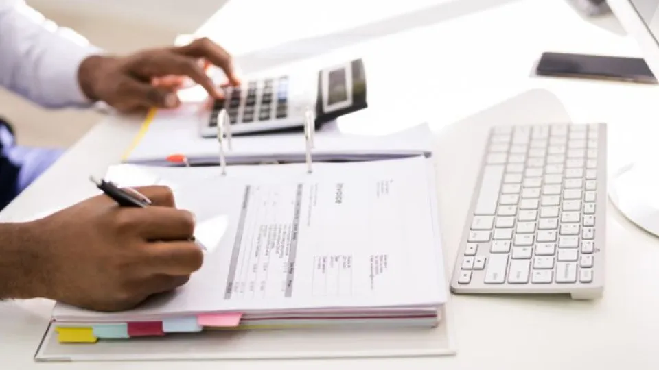 Mãos de homem em cima de dossier aberto com separadores a escrever como representação do cálculo do LTV