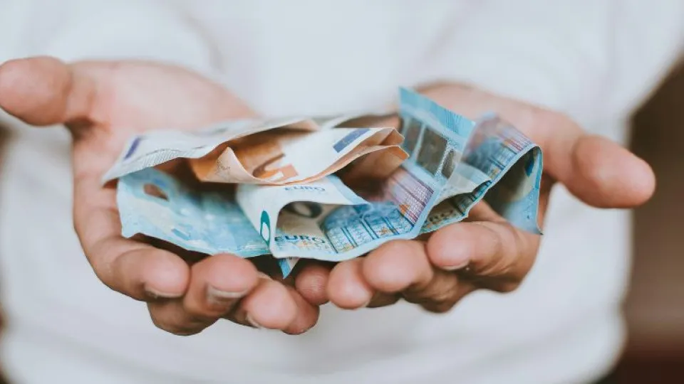 Mãos com notas de euros simbolizando IMI