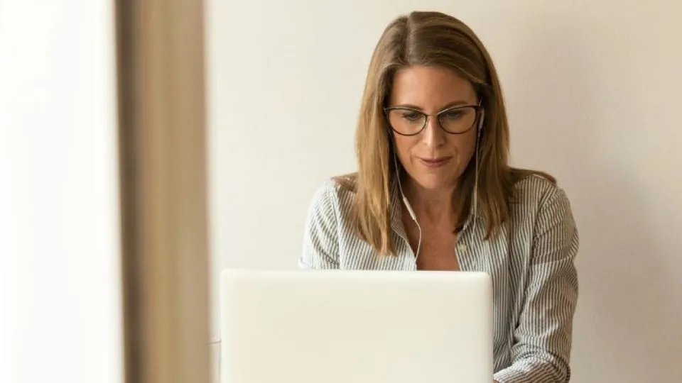 Mulher de óculos em frente de computador com fones a atentar a fraude