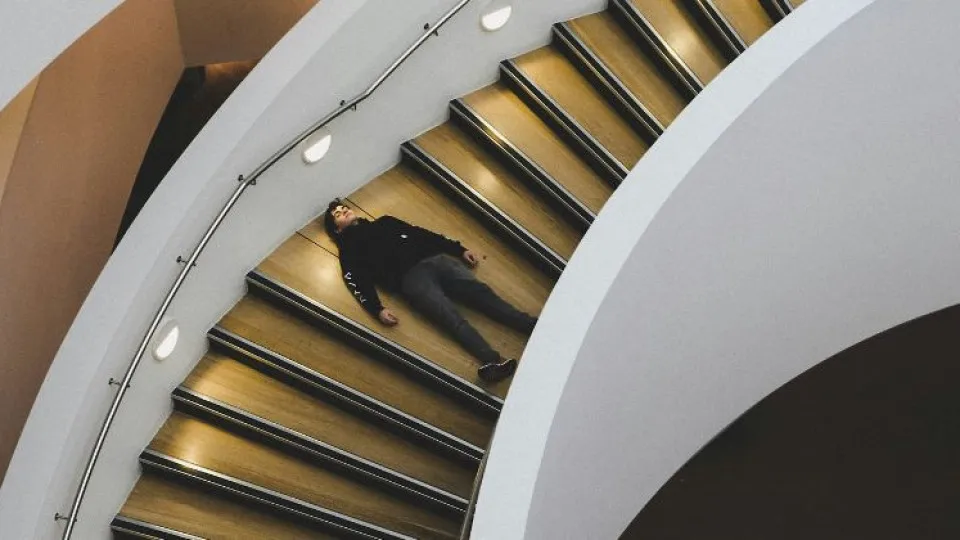 Escadas em descida com rapaz deitado no meio das mesmas