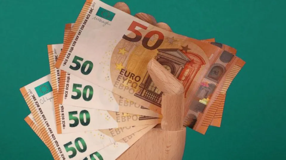 Mão de madeira a segurar notas de 50 euros para simbolizar inflação