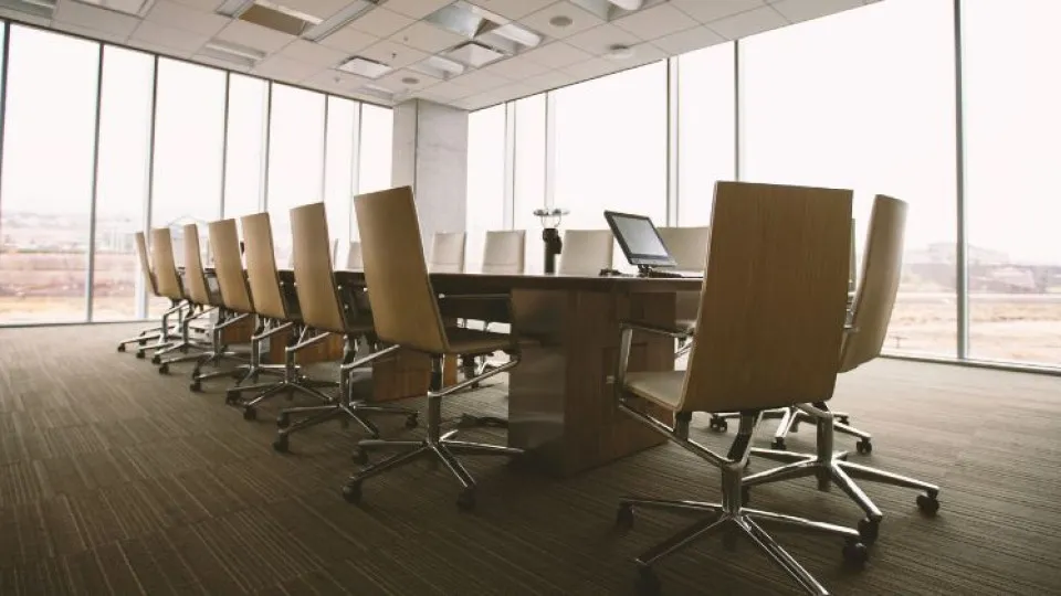 Sala de reuniões com janelas e mesa com cadeiras em volta