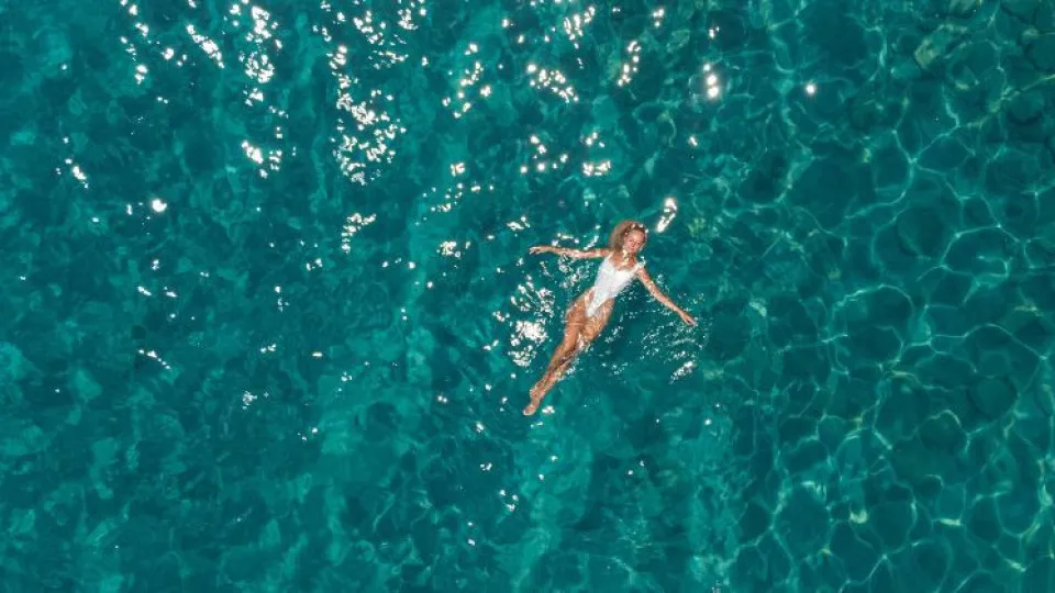 Mulher a boiar sob mar azul simbolizando férias