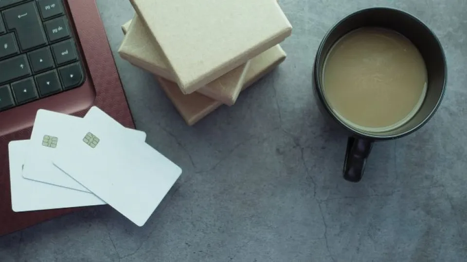Cartões bancários ao lado de um portátil e uma caneca de café, simbolizando a análise e melhoria do score de crédito.