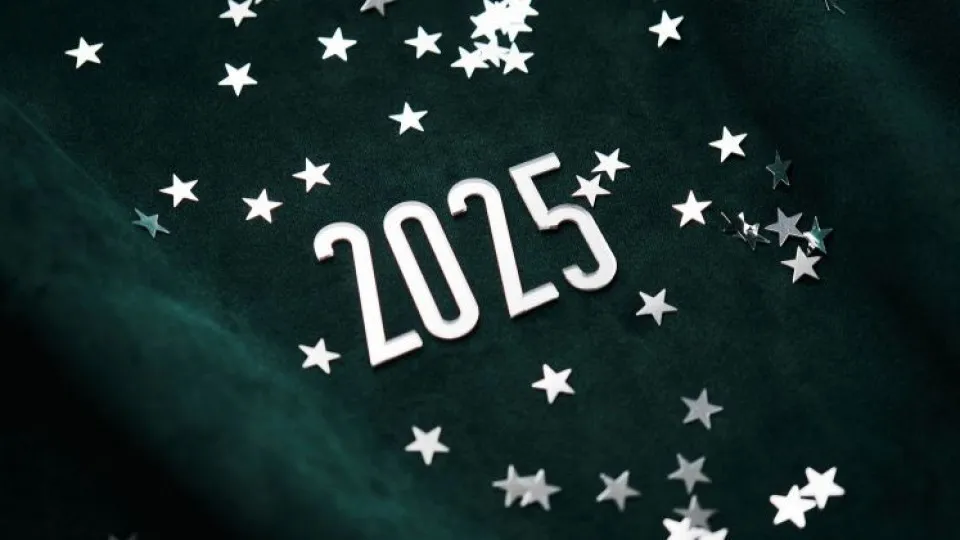 Número 2025 em destaque sobre fundo escuro com estrelas prateadas - simboliza o novo ano.