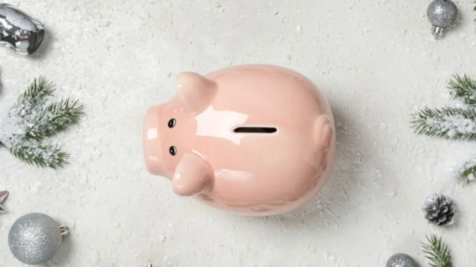Mealheiro em forma de porco rodeado de decorações natalícias, simbolizando poupança nos gastos de Natal.