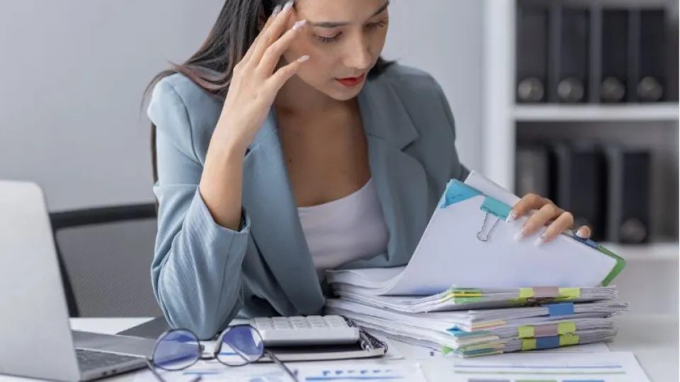 Pessoa a analisar vários documentos financeiros sobre uma secretária, representando a gestão de dívidas