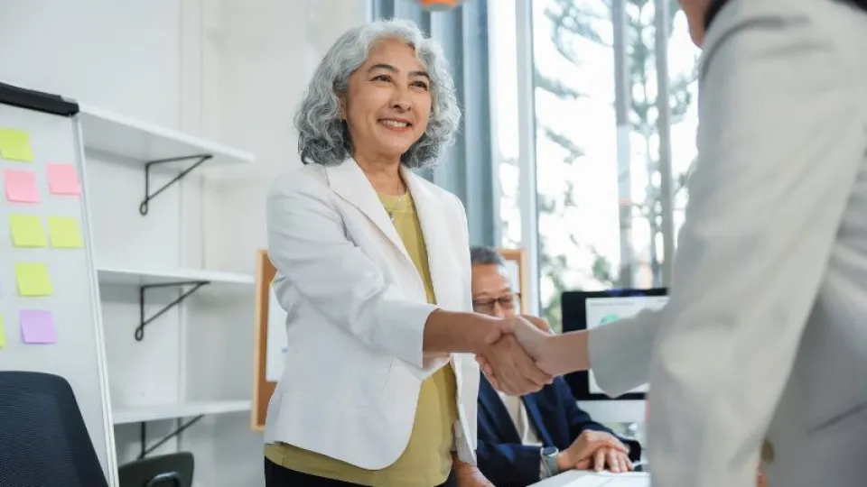 Senhora idosa a dar um aperto de mão a outra senhora despedindo-se porque vai para a reforma