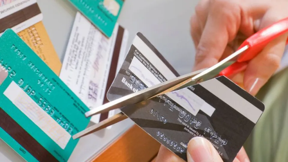 Pessoa a cortar um cartão de crédito com uma tesoura, simbolizando o fim de dívidas ou cancelamento de cartões.