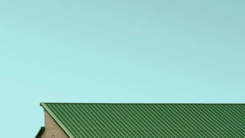 Céu azul e telhado verde de uma casa a aparecer