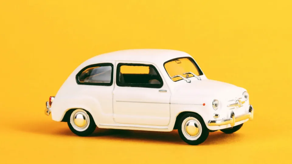 Carro clássico branco em fundo amarelo - representação visual do tema automóvel relacionado com impostos como o IUC.