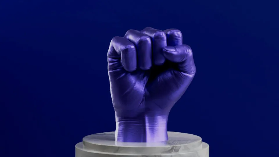 Punho erguido em roxo sobre pedestal de mármore, simbolizando força e reivindicação de direitos laborais ou prémios salariais.