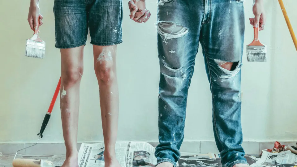 Interior de uma casa em remodelação com folhas de jornal no chão e casal sujo de tinta