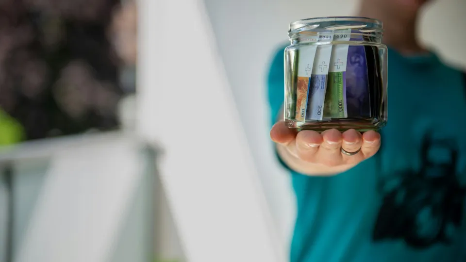 Pessoa a segurar um frasco com notas de euro, simbolizando a poupança e a organização financeira alcançada com o crédito consolidado.