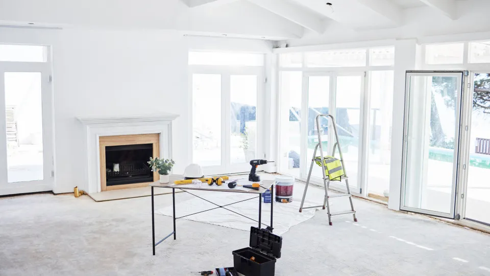 Sala em obras com ferramentas, escadote e materiais de construção usados em remodelação.