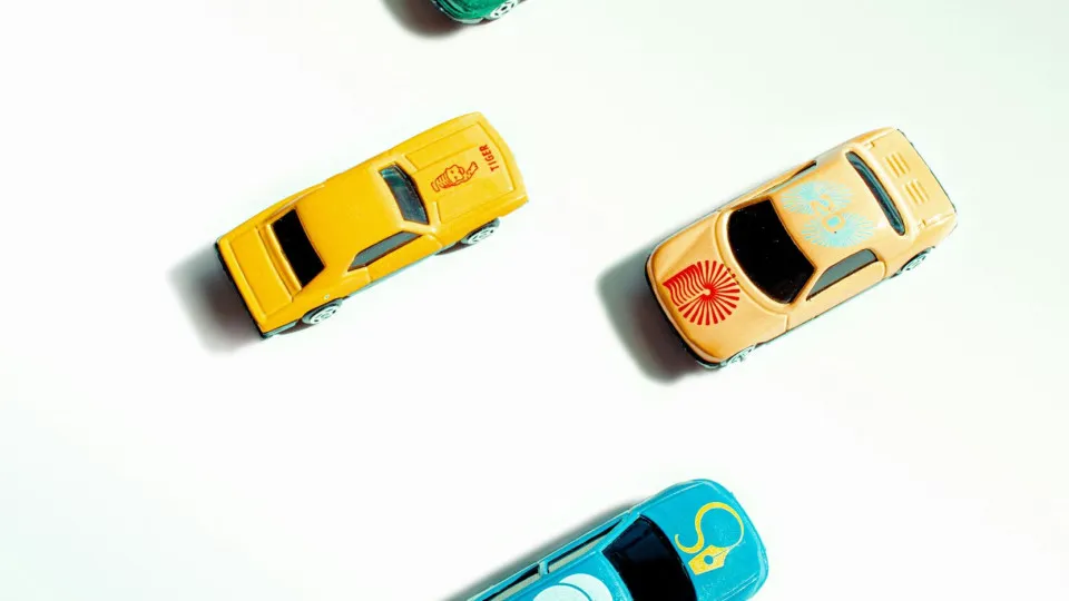 Quatro carrinhos em miniatura vistos de cima, representando diferentes opções de automóveis financiados através de crédito automóvel.