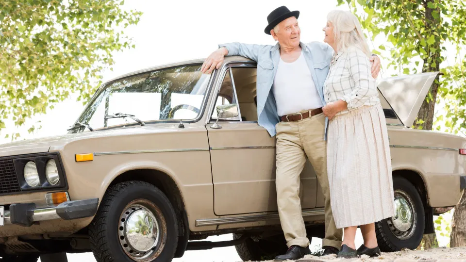Casal sénior encostado ao carro, simbolizando decisões importantes na idade madura, como pedir crédito habitação.