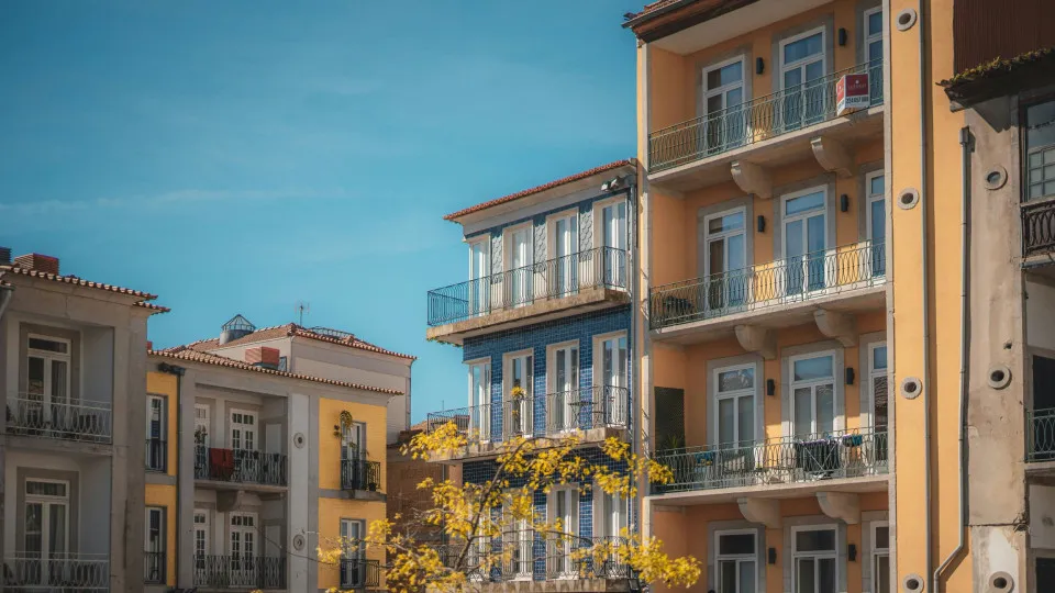 Casa e símbolo de percentagem sobre moedas, representando o impacto do spread nas taxas de juro do crédito habitação.